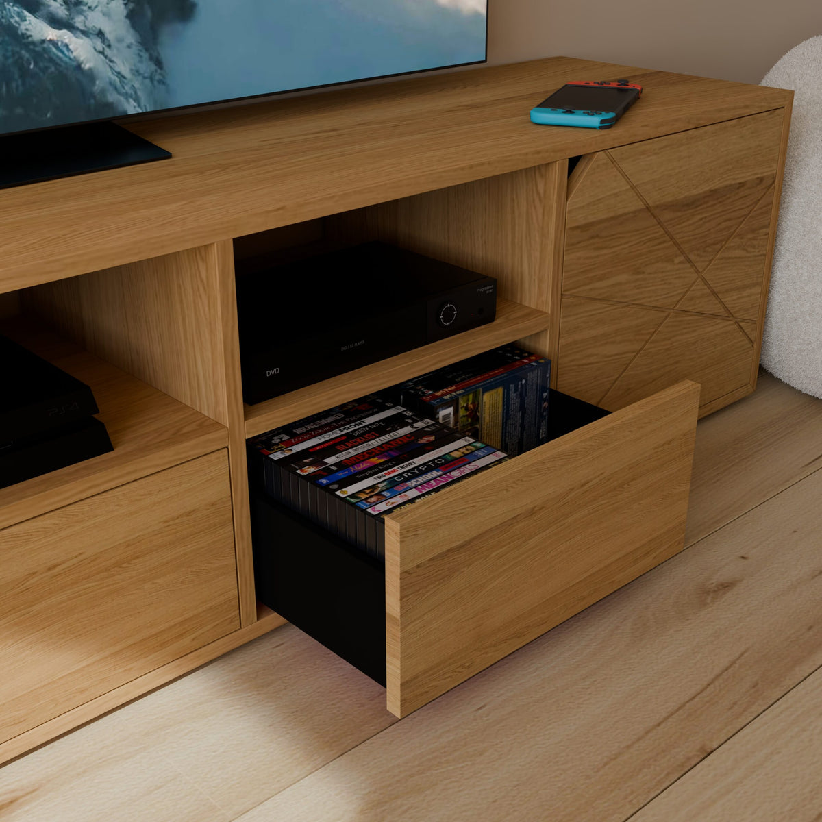 Gros plan sur un tiroir coulissant noir intégré dans un meuble en bois, contenant une collection de boîtiers DVD rangés verticalement. Au-dessus du tiroir, une niche abrite un lecteur DVD/Blu-ray. Une console de jeux est visible sur le plateau supérieur.