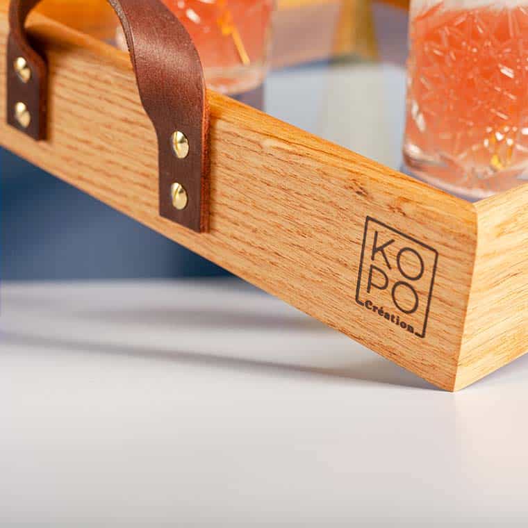 détail sur le logo kopo creation sur le plateau de service en bois massif et verre trempé