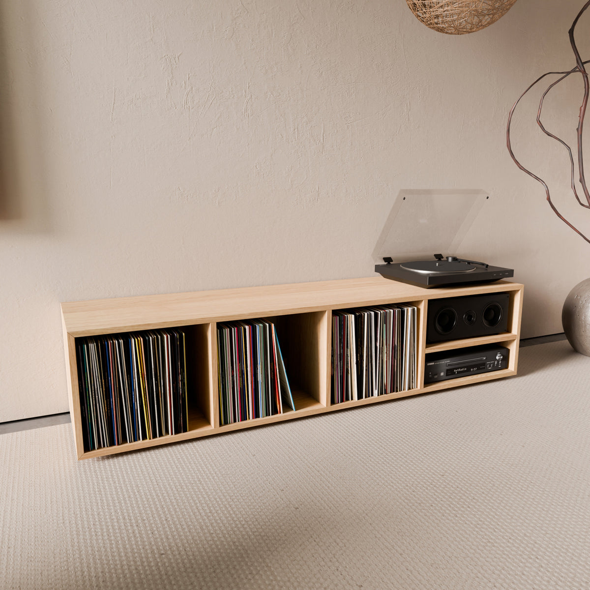 Banquette de rangement pour vinyles en chêne massif avec coussin vert, installée dans un salon au style épuré avec une platine vinyle posée sur le plateau.